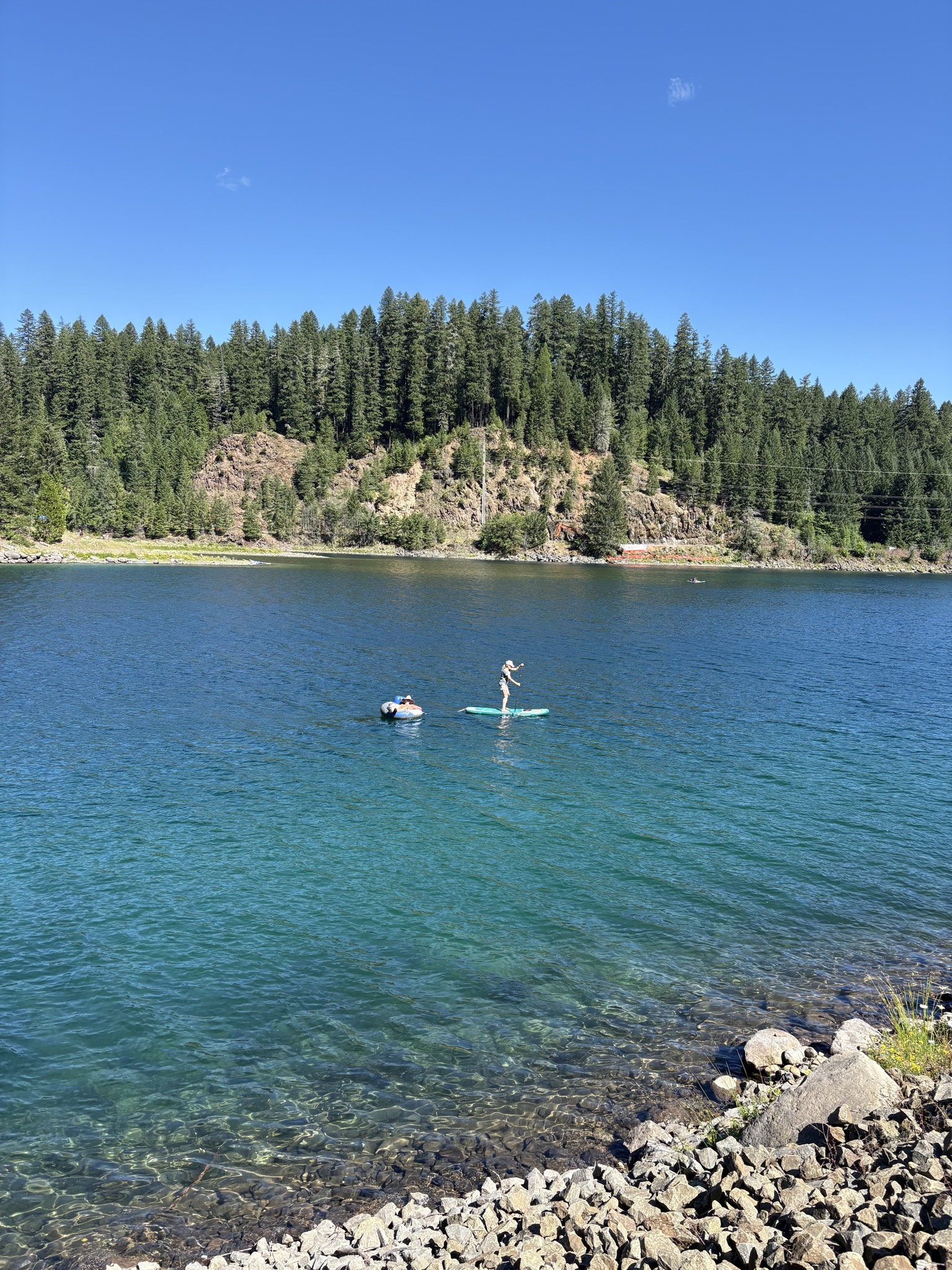 A paddleboarder and a friend on a floatie enjoying the calm blue water near Marcy's Blue Pool pin